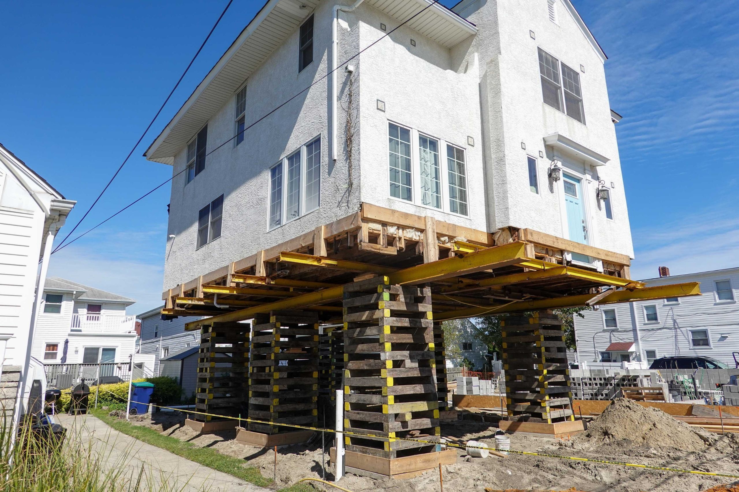 A team of professionals using specialized equipment to raise a house in South Florida, preparing it for elevation and renovation